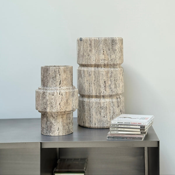 Set of two stone-textured cylindrical vases on a metallic surface with a light gray background